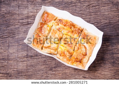 dessert style of fried roti with banana in white paper plate on wooden table top