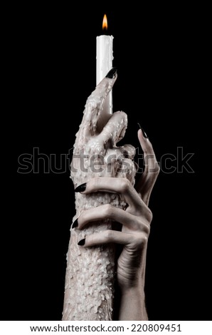 Hand holds a candle witches, black nails, lit candle, hand witches, the devil\'s hand, halloween theme, black background, hand in wax, ritual, solitude, horror, monster