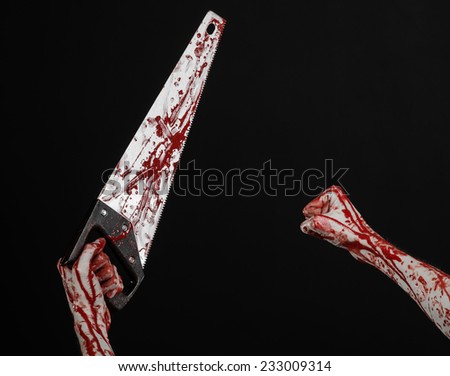 Halloween theme: bloody hand holding a bloody saw on a black background