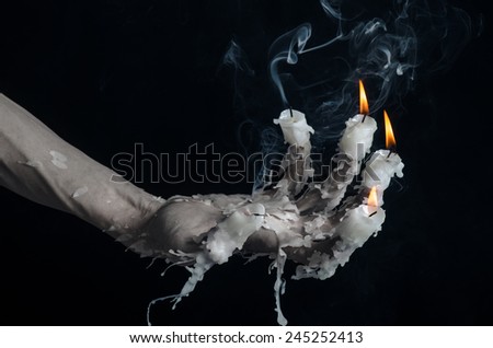Halloween theme: on the hand wearing a candle and dripping melted wax on black isolated background