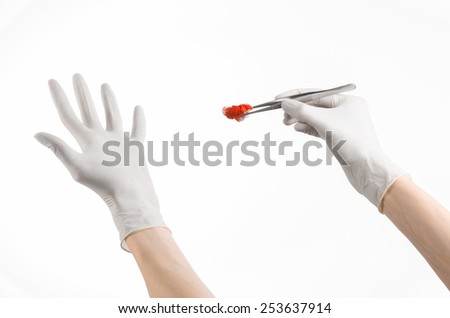 Surgery and Medical theme: doctor\'s hand in a white glove holding a surgical clip with a bloody tampon isolated on a white background in studio