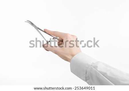 Surgical and Medical theme: doctor\'s hand in a white lab coat holding a surgical clamp scissors isolated on a white background in studio