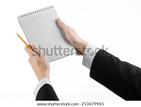 Business and reporter topic: the hand of a journalist in a black suit holding a notebook with a pencil on a white background isolated