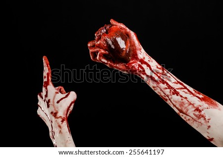 Blood and Halloween theme: terrible bloody hand hold torn bleeding human heart isolated on black background in studio