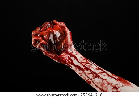 Blood and Halloween theme: terrible bloody hand hold torn bleeding human heart isolated on black background in studio