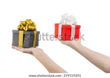 The theme of celebrations and gifts: hand holding two gift wrapped in red box with white ribbon and bow and a black box with gold ribbon, the most beautiful gift isolated on white background in studio