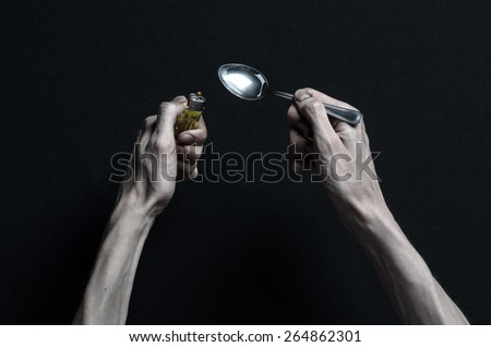 The fight against drugs and drug addiction topic: addict hand holding a spoon with the drug and the second hand heats spoon with a lighter on a dark background in the studio