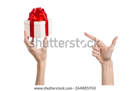 The theme of celebrations and gifts: hand holding a gift wrapped in white box with red ribbon and bow, the most beautiful gift isolated on white background in studio