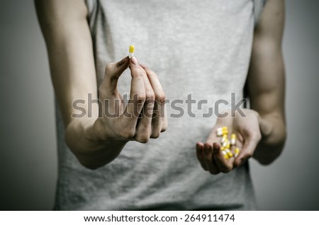 The fight against drugs and drug addiction topic: addict holding a narcotic pills on a dark background
