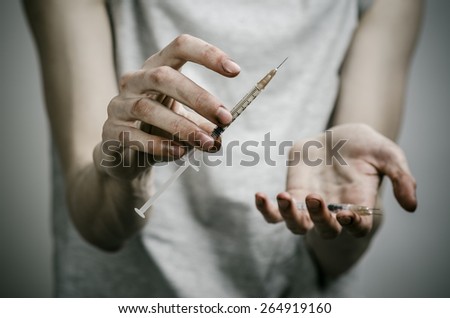 The fight against drugs and drug addiction topic: skinny dirty addict holding a syringe with a drug on a dark background
