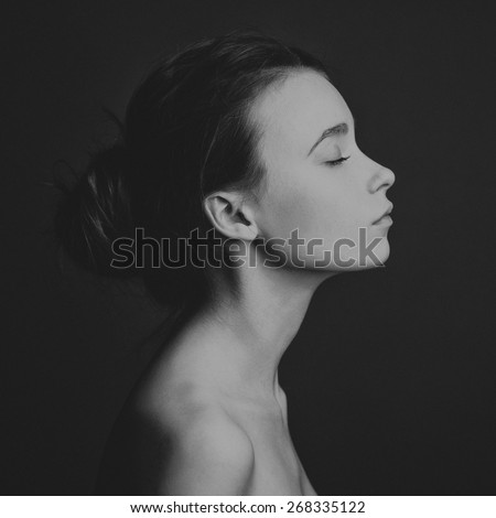 Dramatic portrait of a girl theme: portrait of a beautiful lonely girl isolated on a dark background in studio