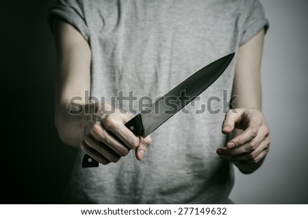 Murder and Halloween theme: a man holding a knife on a gray background