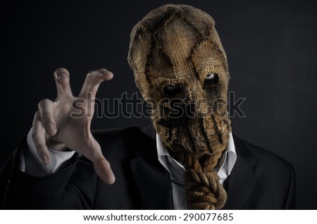 Fear and Halloween Theme: creepy killer in a mask on a dark background in the studio