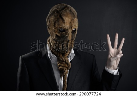 Fear and Halloween Theme: creepy killer in a mask on a dark background in the studio
