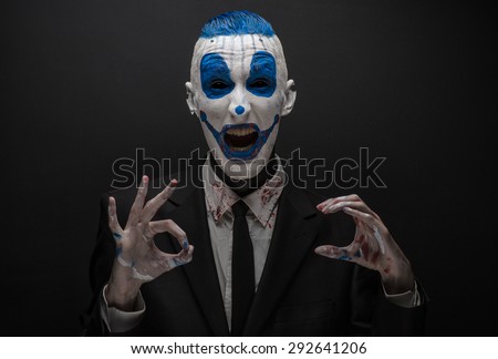 Terrible clown and Halloween theme: Blue Crazy clown in black suit isolated on a dark background in the studio