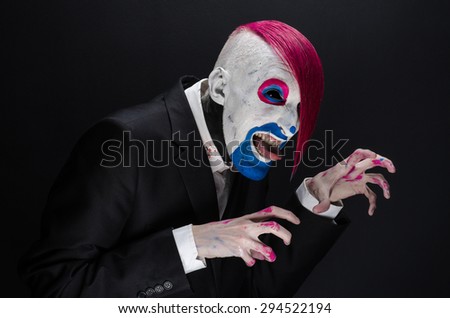 Clown and Halloween theme: Scary clown with pink hair in a black jacket on a dark background in the studio