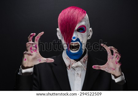 Clown and Halloween theme: Scary clown with pink hair in a black jacket on a dark background in the studio