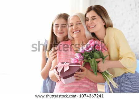 Young woman with daughter congratulating mature family member at home. Happy Mother\'s Day