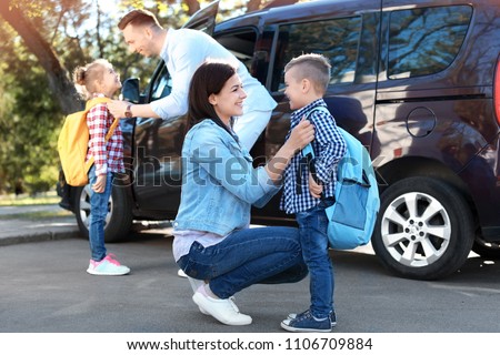 Young parents saying goodbye to their little children near school