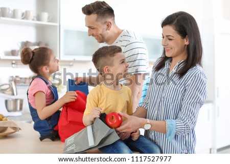 Young parents helping their little children get ready for school at home