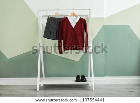 School uniform for girl on rack near color wall