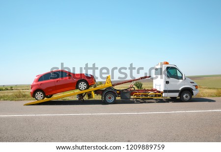 Tow truck with broken car on country road