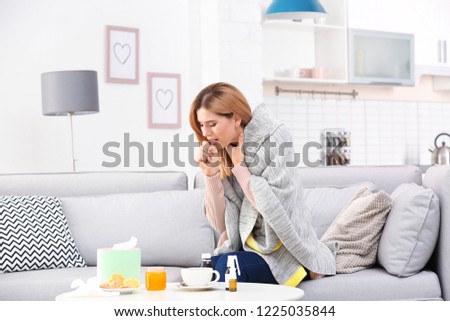 Woman suffering from cough and cold on sofa at home