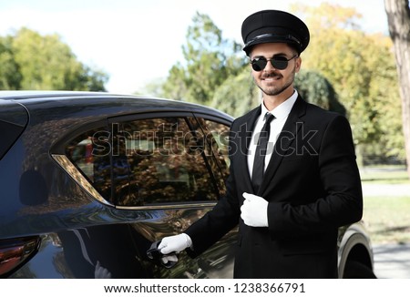 Young handsome driver opening luxury car door. Chauffeur service
