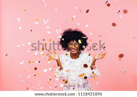 Celebrating happiness, young woman with big smile throwing confetti