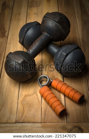 Hand Gripper and rust dumbbell on wooden