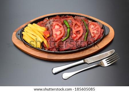 Traditional Turkish Bursa iskender kebap doner served with special red sauce and yogurt in the middle, garnished with grilled tomatoes and peppers