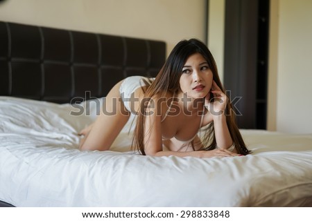 sexy brunette woman on the bed wearing white bikini