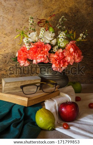 Still life with glasses resting on the book with fruits and flowers in a vase.