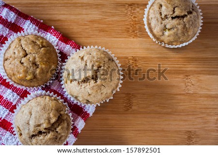 Muffins on a wooden counter with a red accent.