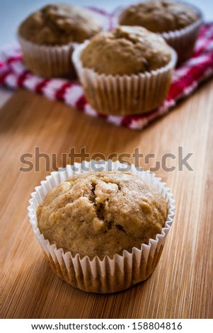 Banana muffins displayed on a wooden backdrop with a red and white accent cloth.