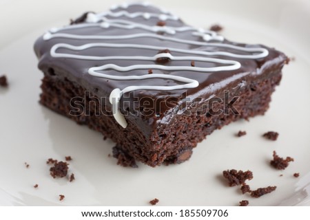 Chocolate Fudge Brownie on a white plate with a drizzle of white chocolate over the top.