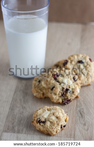 Oatmeal cookies with cranberries and white chocolate chunks on a wooden counter top.