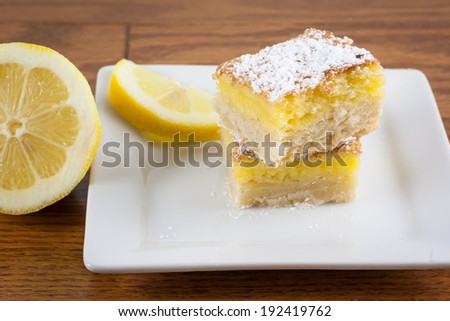 Lemon squares on a white plate and dusted with powdered sugar.