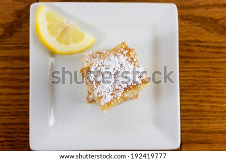 Lemon squares on a white plate and dusted with powdered sugar.