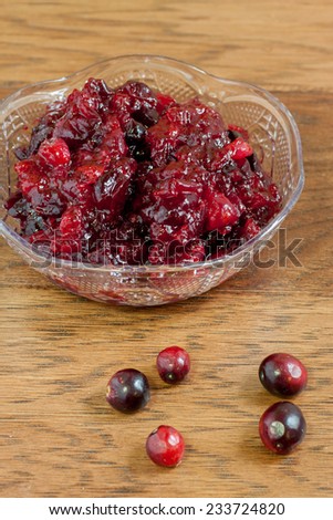 Rustic homemade cranberry sauce in a small crystal dish on a wooden table.