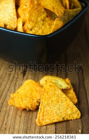 cheese flavored tortilla chips in a dark bowl on a wooden table.