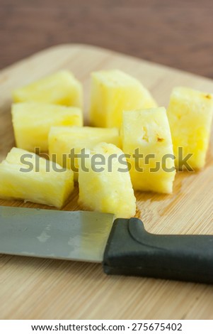 Fresh pineapple chunks on a bamboo cutting board, lite by the early morning sunlight.