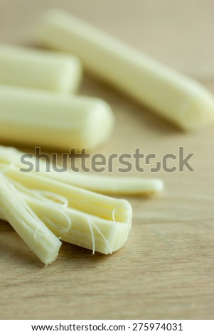 Sticks of mozzerella string cheese on a light colored table top.
