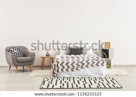 Stylish furniture with big bed near light wall