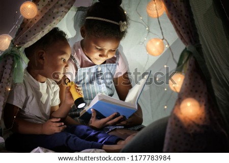 Little African-American children reading bedtime story in hovel