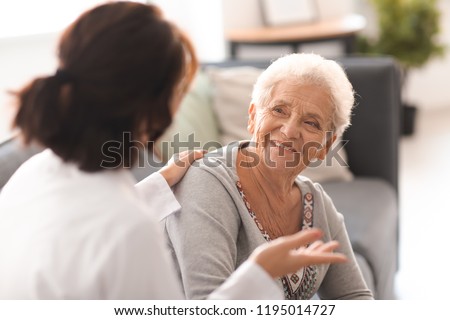 Young doctor visiting elderly woman at home