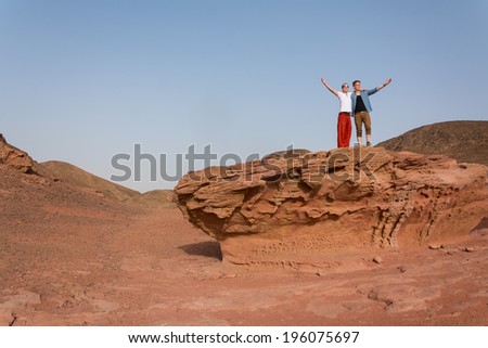Concept success: Two guys raise their arms in the desert