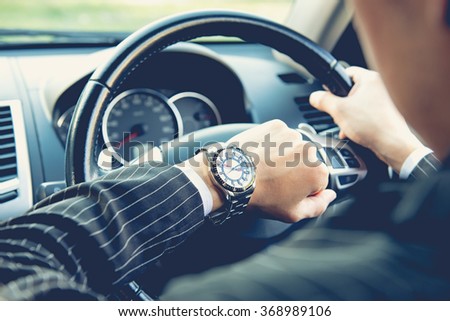 Man driving a car and looking at watch ,business concept ,vintage tone