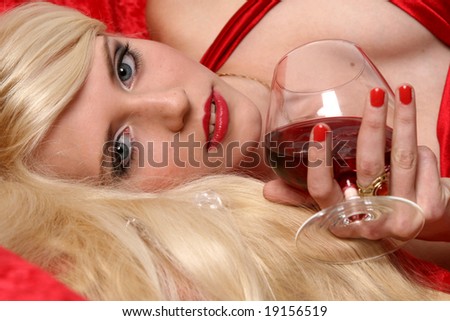 Close-up portrait of beautiful woman with glass red wine glass red wine on red background