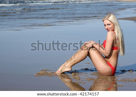 Beautiful young woman in red bikini on seashore